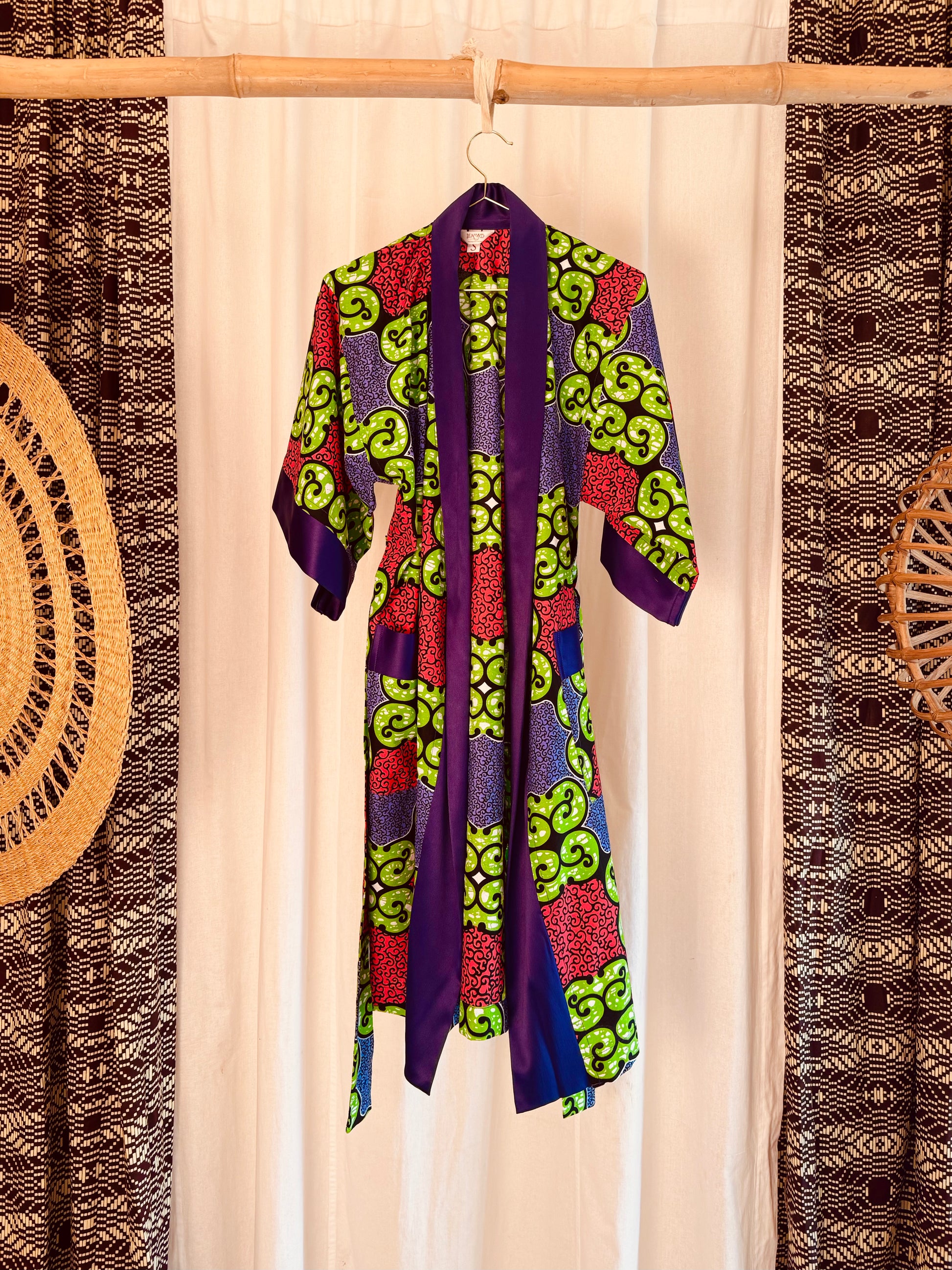 Colorful patterned robe hanging on a rack with decorative elements in the background