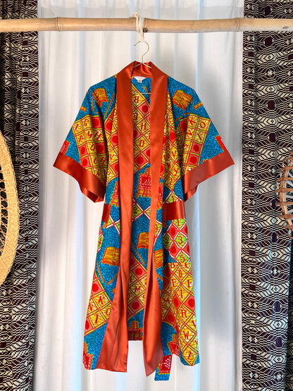 Colorful patterned garment hanging on a rack with a white curtain background