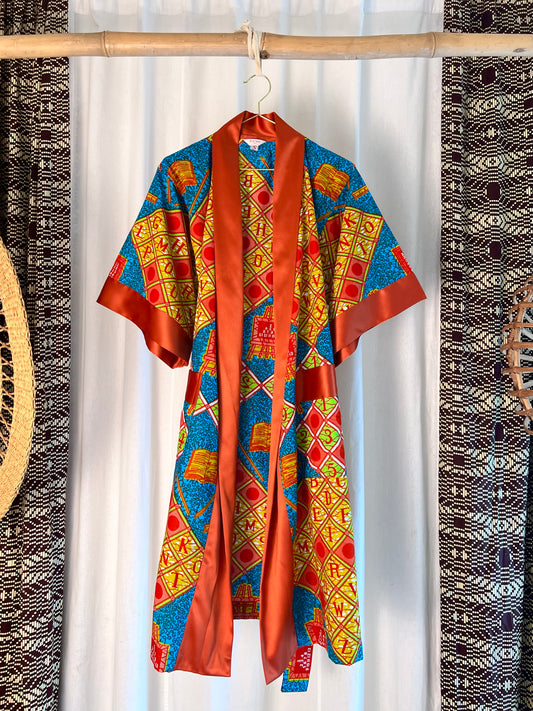 Colorful patterned garment hanging on a rack with a white curtain background