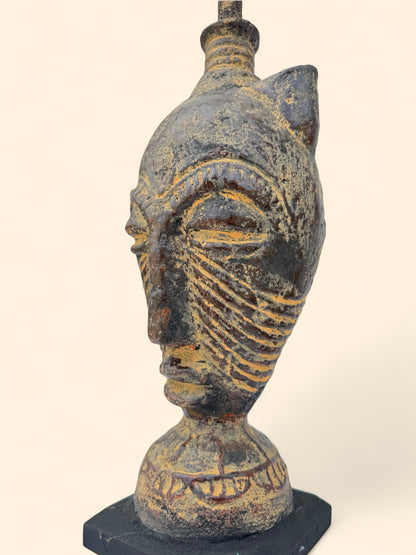 Ceramic sculpture of a face with intricate designs on a white background