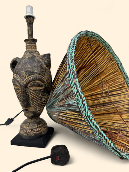 Decorative lamp with African mask design and woven shade on a beige background